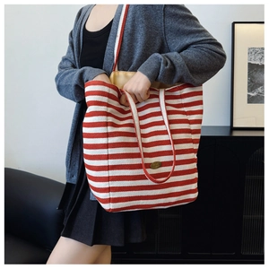 Close-up of red and white striped canvas tote bag with handmade metal tag detail