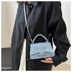 Crossbody bag in light blue faux leather styled with a black coat and white skirt