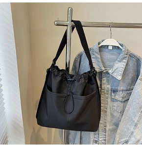 Close-up of black drawstring tote bag with dual front pockets and adjustable strap