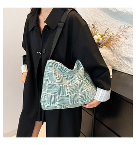 Detail of green and white geometric woven tote bag with adjustable black shoulder strap