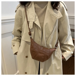 Sac croissant en cuir marron porté avec un trench beige pour un style d'automne épuré