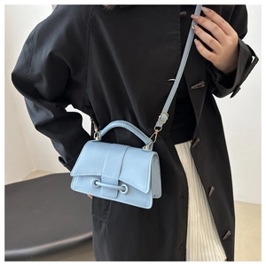 Detail view of light blue leather crossbody bag with dual ring flap and gold hardware