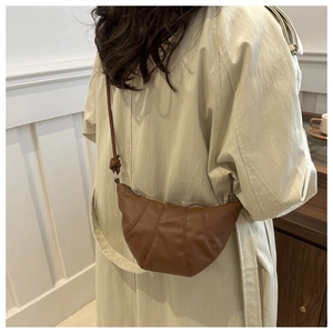 Détail d'un sac croissant en cuir marron avec texture piquée et bandoulière à nœuds