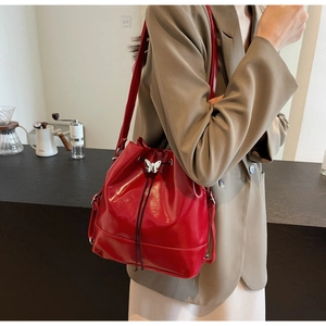Détail du sac seau rouge avec cordon de serrage et boucle papillon blanche