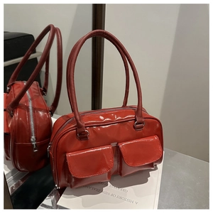 Détail du sac à main rouge en cuir verni avec deux poches frontales et fermeture éclair