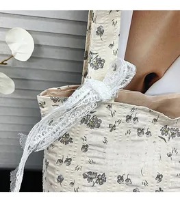 Detailed view of seersucker tote bag with floral print and white lace bow decoration