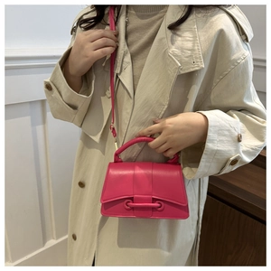Detail of rose pink mini crossbody bag with curved base and polished leather finish
