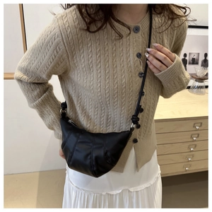 Détail d'un sac croissant plissé noir porté par un mannequin dans un cadre chaleureux