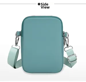 Side view of small crossbody phone bag in light teal fabric with metallic D-rings and zipper