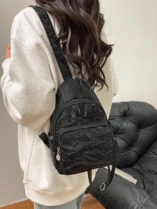 Minimalist black wrinkled nylon backpack with multi-zipper compartments and adjustable straps