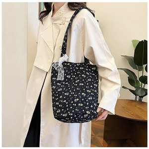 Detailed view of black floral tote bag with white lace bow and quilted fabric design