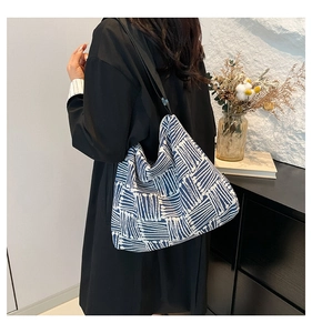 Detail of navy blue canvas tote bag with white geometric pattern and black strap