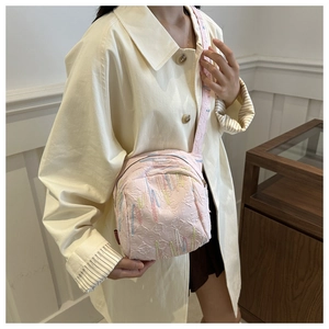Détail du sac à bandoulière rose clair avec coutures colorées et large sangle texturée