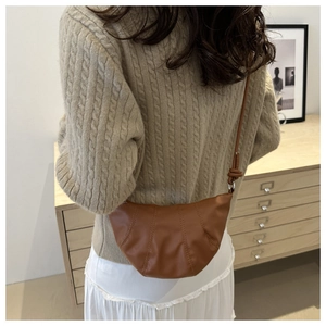 Sac croissant marron en cuir avec bandoulière et détails plissés portés par le mannequin