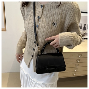 Elegant black leather square handbag styled with a beige sweater and white skirt