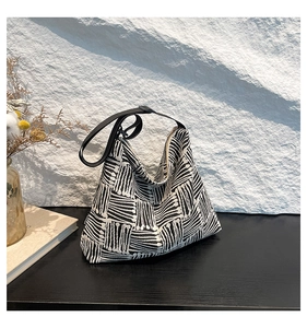 Detail of black and white striped jacquard tote bag with FASHION label on a stone background