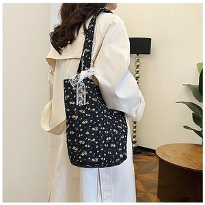 Detail of black floral tote bag with white lace bow and quilted fabric texture