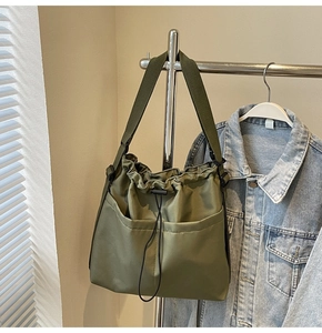 Detail view of olive green drawstring bucket bag with large dual front pockets