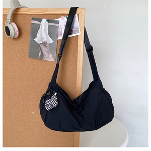 Detail van de zwarte nylon halve maan crossbody tas met hartvormige tashanger