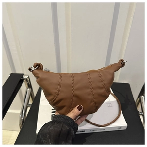 Détail de la couture verticale sur un sac croissant marron avec bandoulière réglable