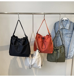 Detail showing colorful drawstring nylon tote bags in black white orange and green