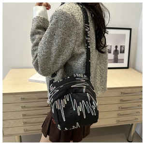 Détail d'un sac bandoulière en nylon noir matelassé avec des broderies ondulées colorées