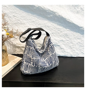 Detail of blue and white geometric striped tote bag with metal zipper on a wooden surface