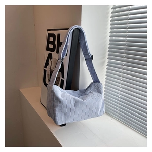 Detail of light blue woven texture shoulder bag on windowsill with natural sunlight
