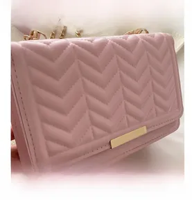 Detail of pink chevron quilted leather surface with elegant gold metal chain and buckle