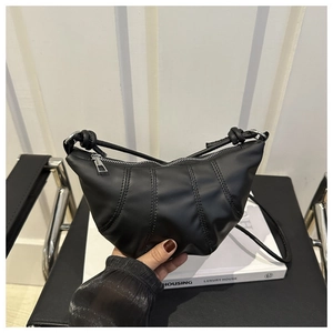 Détail du sac croissant en cuir noir avec coutures plissées et fermeture éclair argentée