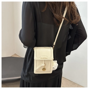 Dettaglio della mini borsa a tracolla bianco crema con ciondolo a pompon e logo
