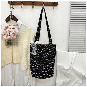 Close-up of black floral pleated tote bag featuring a white lace bow and yellow flower pattern