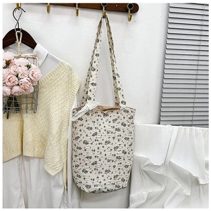 Detailed view of cream floral tote bag with white lace bow on a wooden hook hanger