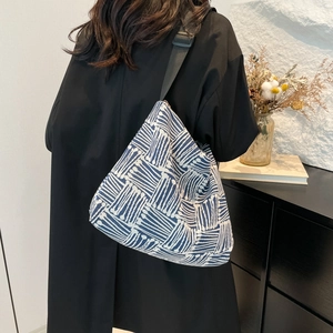 Minimalist blue and white geometric canvas tote bag with adjustable black strap shown on model