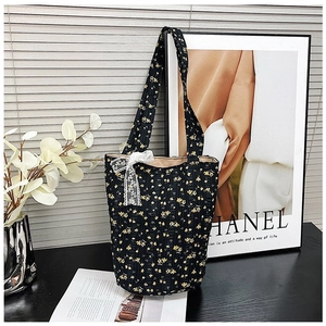 Detail of floral quilted tote bag featuring a white lace bow and elegant black fabric pattern