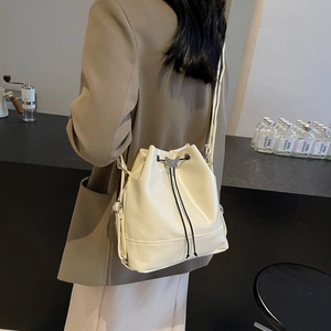 Sac seau chic en similicuir beige avec détail papillon porté par un mannequin femme