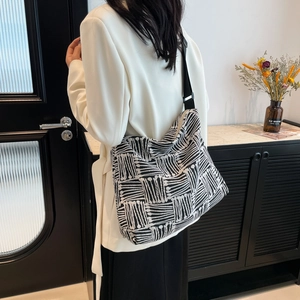Black and white striped canvas tote bag worn by a model in a minimalist setting