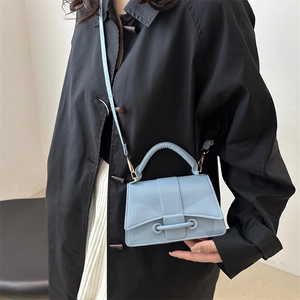 Minimalist light blue crossbody bag with trapezoid structure and cylindrical handle