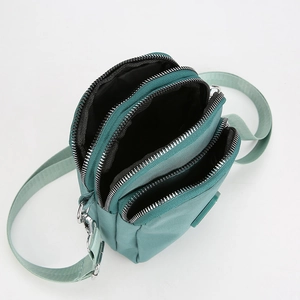 Detail view of the mint green crossbody phone bag showing three zippered compartments