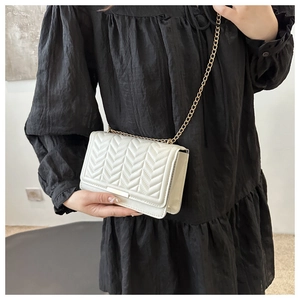 Detail of cream white crossbody bag with V-shaped quilting and gold metal buckle
