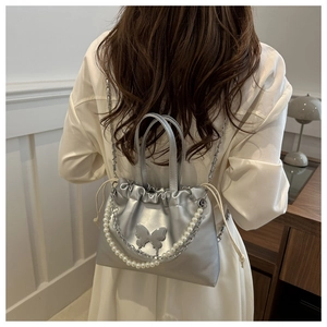 Détail du sac seau argenté avec décoration papillon 3D et chaîne en perles