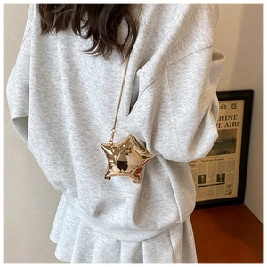Model met een gouden stervormige acryl avondtas voorzien van een fijne metalen ketting