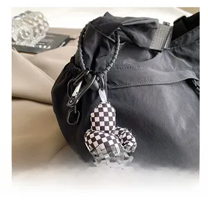 Detail van zwarte nylon shopper met geblokte knoopbedel en metalen gespsluiting