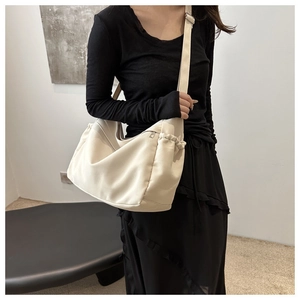 Detail of minimalist beige bucket bag with adjustable shoulder strap and side pleats