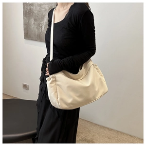 Detailed view of cream nylon bucket bag worn by model over a black dress in a studio