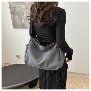 Detail view of large dark grey nylon bucket bag with wide strap and side pockets