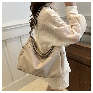 Detailed side view of beige canvas bucket bag with drawstring and shoulder strap on model