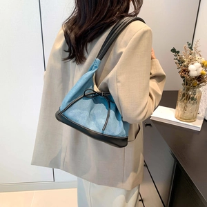 Blue denim underarm hobo bag with black leather trim and bow detail on a casual model