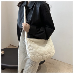 Gros plan sur un sac cabas matelassé crème avec motif cœur porté par un mannequin