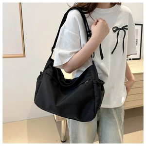 Lifestyle view of a black large capacity canvas tote bag worn by a model in casual outfit